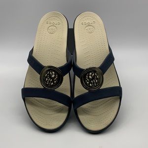 Crocs Sanrah Circle women’s slip-on sandals with gold tone medallion. Size 10.